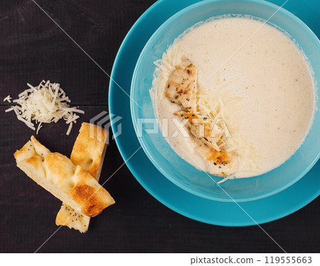 Chicken cream soup served in a blue bowl on a dark wooden background Chicken cream soup served in a blue bowl on a dark wooden background 119555663