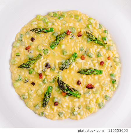 Delicious risotto with asparagus and pancetta being served on white plate Delicious risotto with asparagus and pancetta being served on white plate 119555693