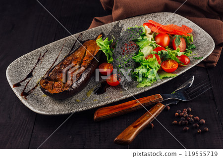 Grilled eggplant served with fresh salad on elegant restaurant table setting 119555719