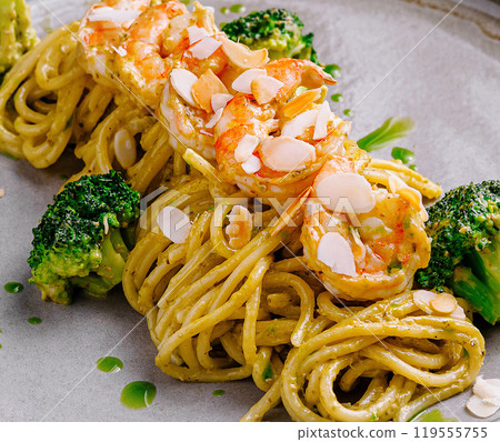 Delicious pasta dish with shrimps, pesto sauce and broccoli on gray plate 119555755