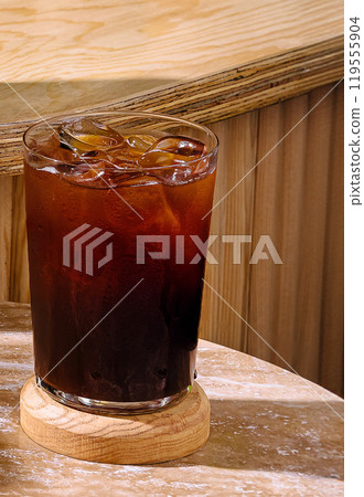 Iced coffee sitting on a wooden coaster on a table 119555904