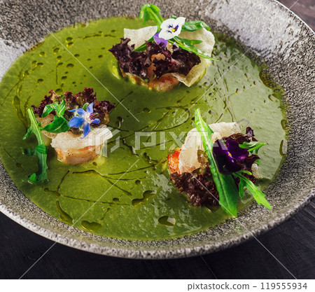 Green cream soup with shrimps and arugula being served on restaurant table 119555934