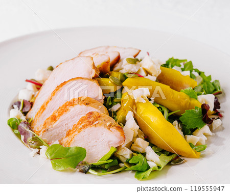 Sliced grilled chicken breast on salad with yellow pepper and parmesan cheese 119555947