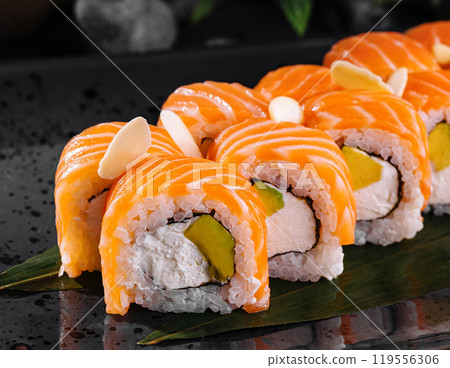 Philadelphia sushi rolls decorated with almond flakes are lying on the black plate Philadelphia sushi rolls decorated with almond flakes are lying on the black plate 119556306