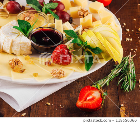 Delicious cheese platter with organic ingredients arranged on wooden table 119556360