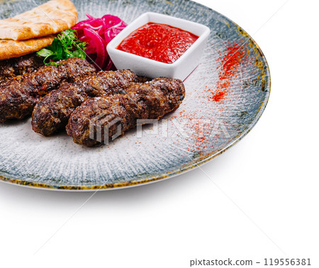 Grilled lula kebab with pita bread, adjika and onion on plate, isolated on white background 119556381