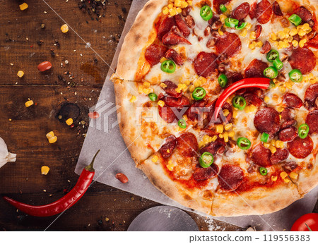 Delicious pizza lying on wooden table background Delicious pizza lying on wooden table background 119556383