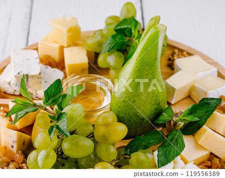 Gourmet cheese plate displayed with grapes and pear on wooden board Gourmet cheese plate displayed with grapes and pear on wooden board 119556389