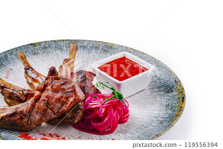 Grilled lamb ribs served on plate with red sauce and onions Grilled lamb ribs served on plate with red sauce and onions 119556394