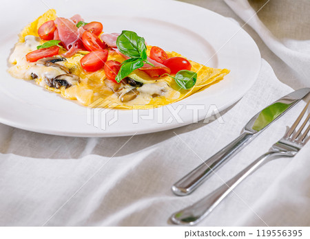 Delicious omelette with ham, vegetables and cheese on white plate for a healthy breakfast Delicious omelette with ham, vegetables and cheese on white plate for a healthy breakfast 119556395
