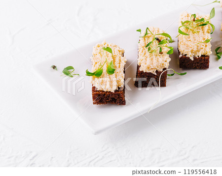 Delicious canapes with cream cheese and greens lying on white plate Delicious canapes with cream cheese and greens lying on white plate 119556418