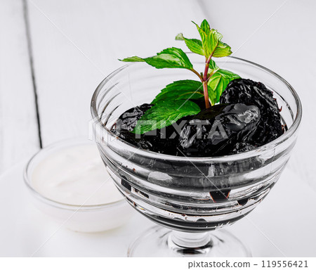 Prunes with mint sprig served in glass on white table 119556421