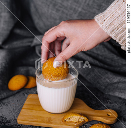 Dipping a cookie into a glass of milk Dipping a cookie into a glass of milk 119556467