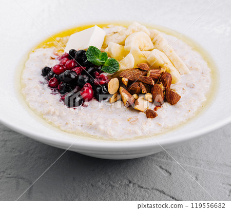 Oatmeal porridge with berries, banana and almonds for healthy breakfast 119556682