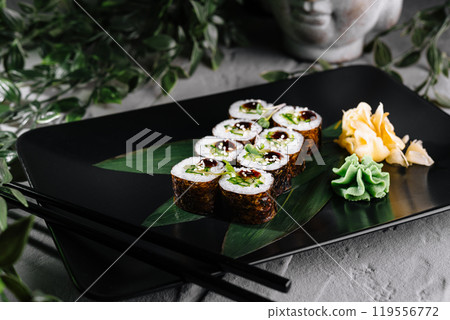 Delicious sushi rolls served on black plate with wasabi and ginger 119556772