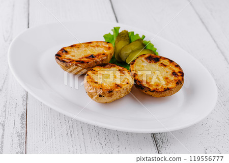 Baked potato with pickles on white plate is standing on white table 119556777