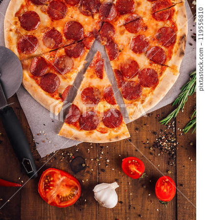 Delicious pepperoni pizza surrounded by fresh ingredients on wooden table 119556810