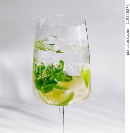 Refreshing summer cocktail with lime and mint leaves in wineglass 119556878