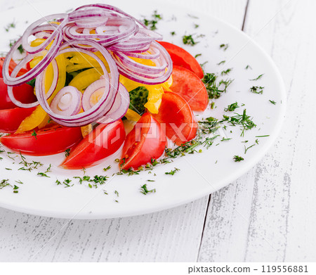 Fresh vegetable salad with red onion rings on white plate 119556881