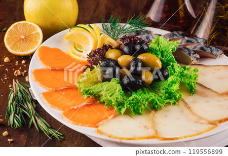 Sliced cold smoked fish platter with salmon and butterfish decorated with greens and olives Sliced cold smoked fish platter with salmon and butterfish decorated with greens and olives 119556899