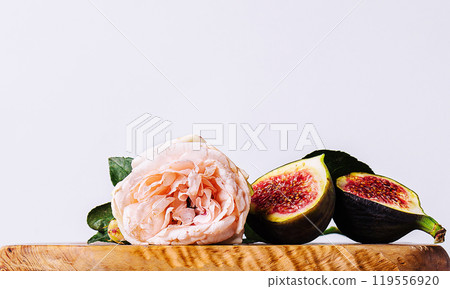 Single pink rose laying on a wooden table with fresh figs Single pink rose laying on a wooden table with fresh figs 119556920