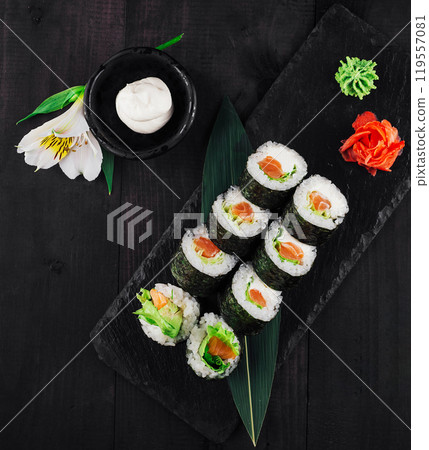 Fresh sushi rolls with salmon and avocado on black stone serving plate 119557081