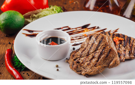 Grilled beef steak with sauce and spices on white plate Grilled beef steak with sauce and spices on white plate 119557098