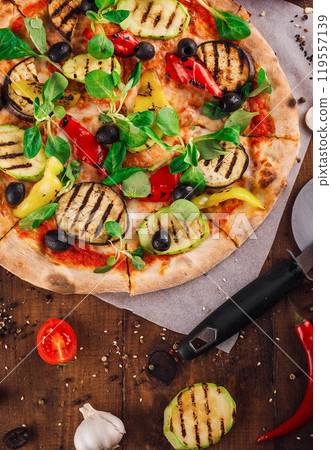 Delicious vegetarian pizza lying on wooden table surrounded by fresh ingredients 119557139