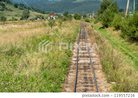 Narrow gauge railway in a mountain village. Rails and sleepers. Railway track. Nature in summer. Travel by train. Carpathians Narrow gauge railway in a mountain village. Rails and sleepers. Railway track. Nature in summer. Travel by train. Carpathians 119557216