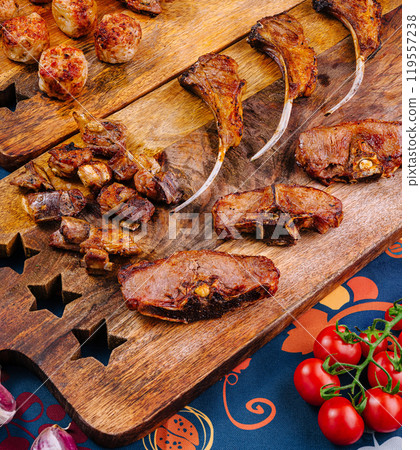 Grilled lamb ribs, meatballs, and veal cuts lying on wooden boards Grilled lamb ribs, meatballs, and veal cuts lying on wooden boards 119557238