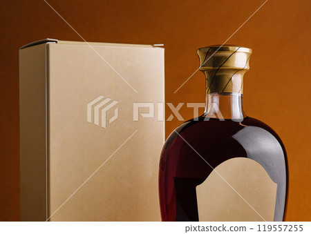 Bottle of alcohol with blank label and cardboard packaging standing on orange background 119557255