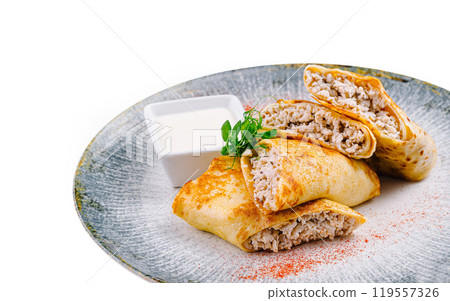 Pancakes with meat filling lying on gray plate with sour cream 119557326