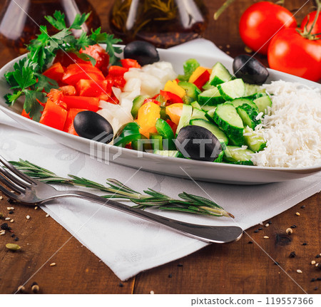 Shopska salad with feta cheese, tomatoes, cucumber and olives resting on a wooden table 119557366