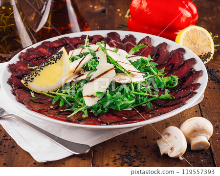 Delicious beef carpaccio with arugula, parmesan cheese and lemon on white plate Delicious beef carpaccio with arugula, parmesan cheese and lemon on white plate 119557393