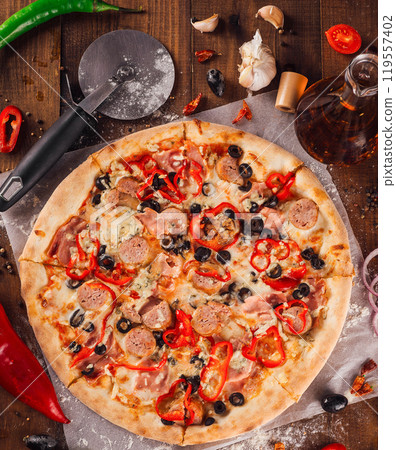 Delicious pizza lying on wooden table surrounded by fresh ingredients 119557402