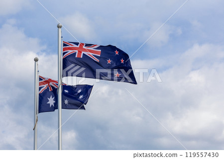 New Zealand and Australia national flags flying side by side against blue sky background New Zealand and Australia national flags flying side by side against blue sky background 119557430