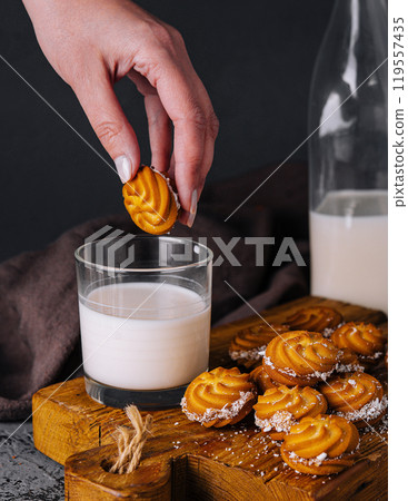 Hand dipping cookie in milk glass on rustic table 119557435