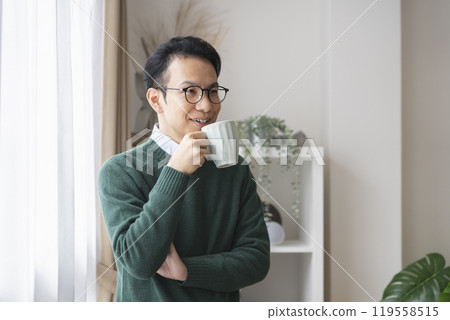 A man in his late 30s drinking from a mug 119558515