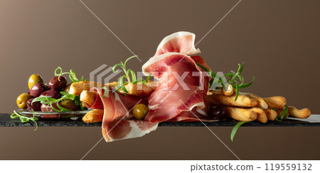 Prosciutto with bread sticks, olives, and rosemary. Prosciutto with bread sticks, olives, and rosemary. 119559132