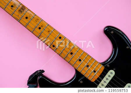 Black electric guitar on pink background. 119559753