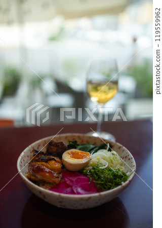 Japanese famous delicious ramen with different ingredients Noodle soup with shiitake, egg and pak choi cabbage on dark background. Glass of white wine Japanese famous delicious ramen with different ingredients Noodle soup with shiitake, egg and pak choi cabbage on dark background. Glass of white wine 119559962