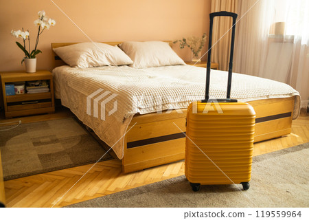 Interior of hotel room with yellow suitcase luggage near bed. Conceptual of travel and vacation.  119559964