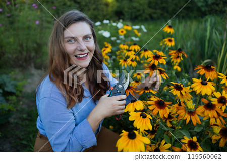 Young gardener cutting little flower plant off with pruner for bouquet. Summer gardening work. Young gardener cutting little flower plant off with pruner for bouquet. Summer gardening work. 119560062