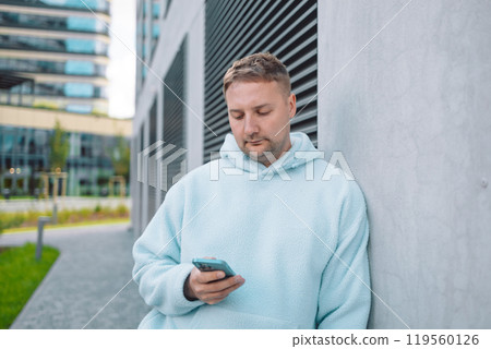 Successful young Caucasian man walking outside office building, engineer software developer programmer smiling and happy using test app on phone Successful young Caucasian man walking outside office building, engineer software developer programmer smiling and happy using test app on phone 119560126