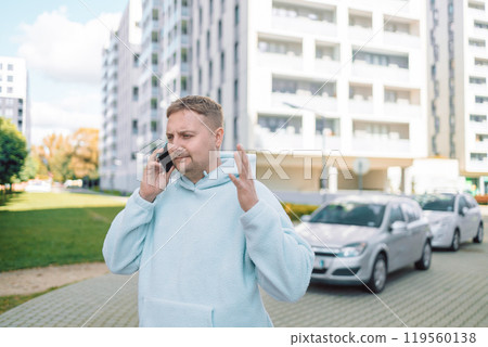 Angry Caucasian 30s man disappointed guy millennial male worried stressed car driver near modern auto on city parking outdoors reading bad news mobile phone problem loss upset 119560138