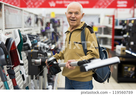 Senor man pensioner buying Upright Vacuum Cleaner in showroom of electrical appliance store 119560789