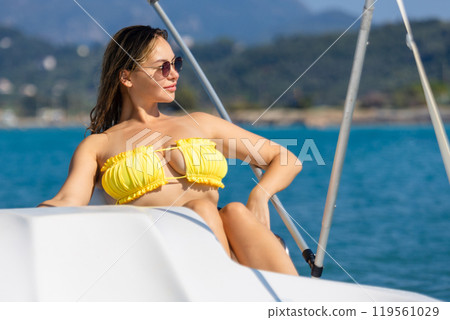 A beautiful girl sits in the captain's seat at the helm on a yacht A beautiful girl sits in the captain's seat at the helm on a yacht 119561029