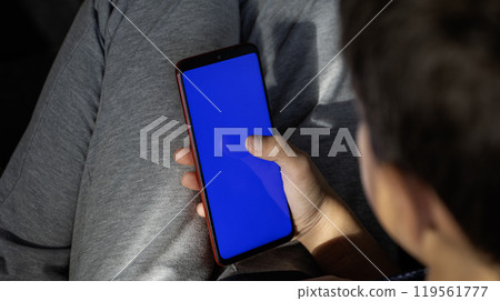 Child looking at phone screen. focus on phone. view from back Child looking at phone screen. focus on phone. view from back 119561777
