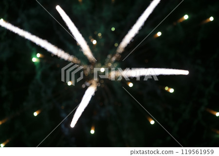 On a black background, blurry light stripes of bokeh from fireworks. Festive dark background. 119561959