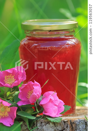 Homemade wild rose jam in the jar on the stump in the forest. Homemade wild rose jam in the jar on the stump in the forest. 119563057